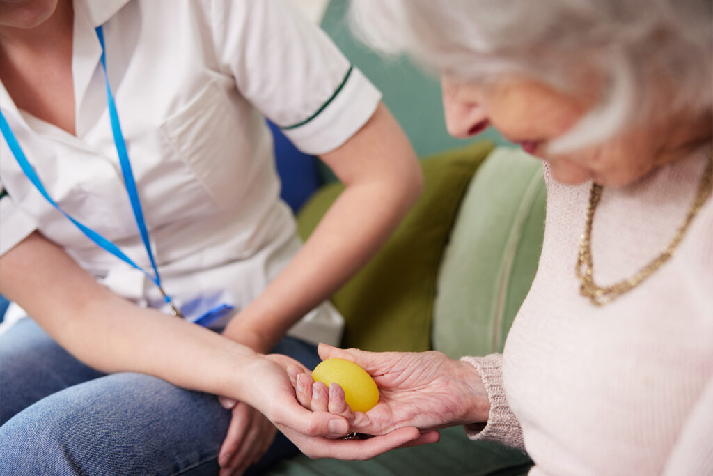 Egotherapeutin kümmert sich um Seniorin bei einer Hand Übung