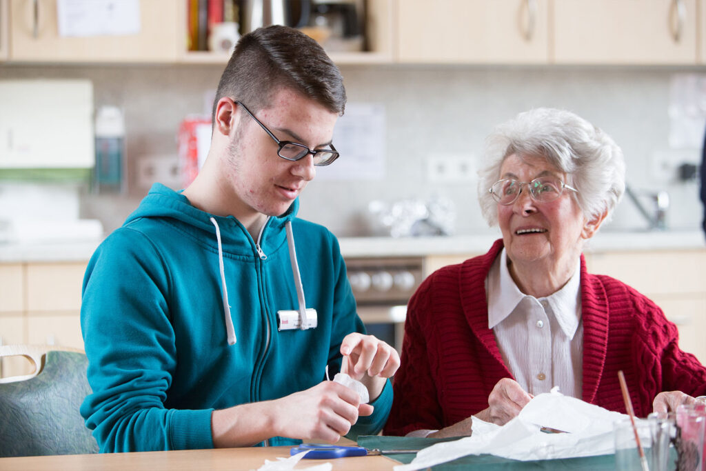 Jugendlicher betreut in seinem FSJ eine Seniorin