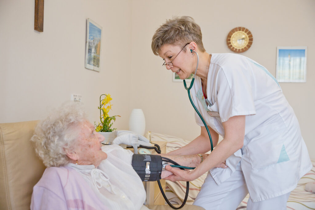 Pflegerin misst den Blutdruck einer Seniorin